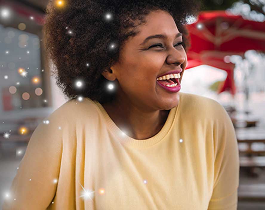 A woman laughing facing right with snow superimposed over her.